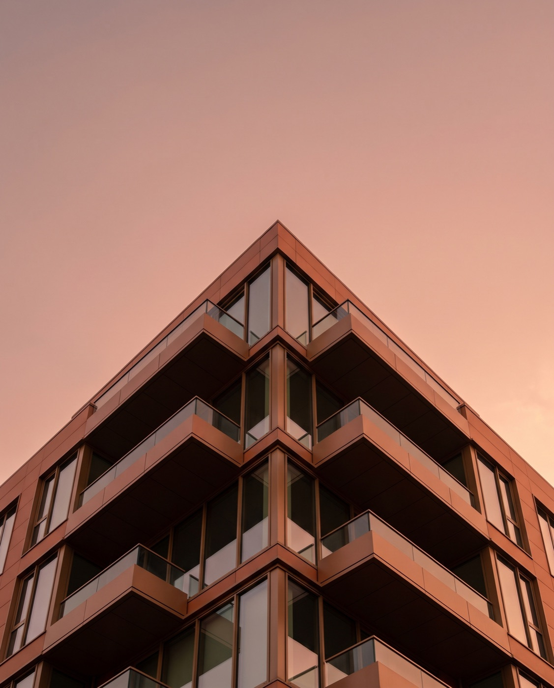 A Makro development's terracotta corner rising against a rose-gold sky
